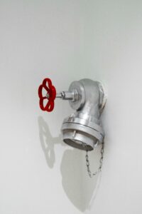 Detailed view of a silver plumbing installation with a red valve on a white wall in Eskişehir.